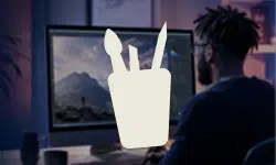 Person seated at a desk, facing a computer monitor displaying a mountain landscape.